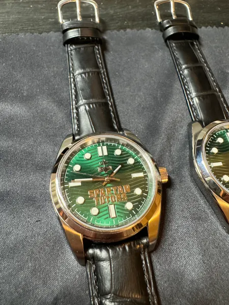 Two matching green-dial watches on black leather straps